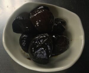 白い小皿に盛られた黒糖ニンニク漬け【無臭ニンニク使用）