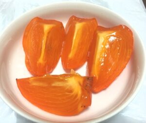 完熟の富士柿が白い皿に切り分けられている画像