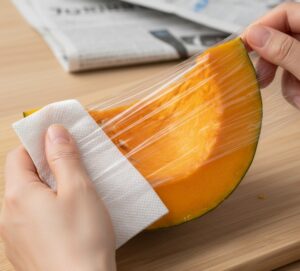 かぼちゃを新聞紙とキッチンペーパーで包む手元
