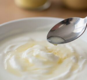 プーンで取り分けたヨーグルトに、透明なホエイ（水分）が分離して浮いている様子