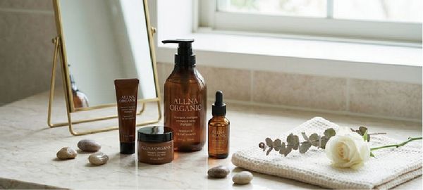 窓辺に置かれたオルナオーガニックオイルと白いバラの画像