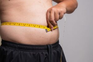40代の男性がお腹にメージャーを当てている画像
