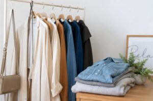 ハンガーにつるされた服と畳まれた服が置かれている画像